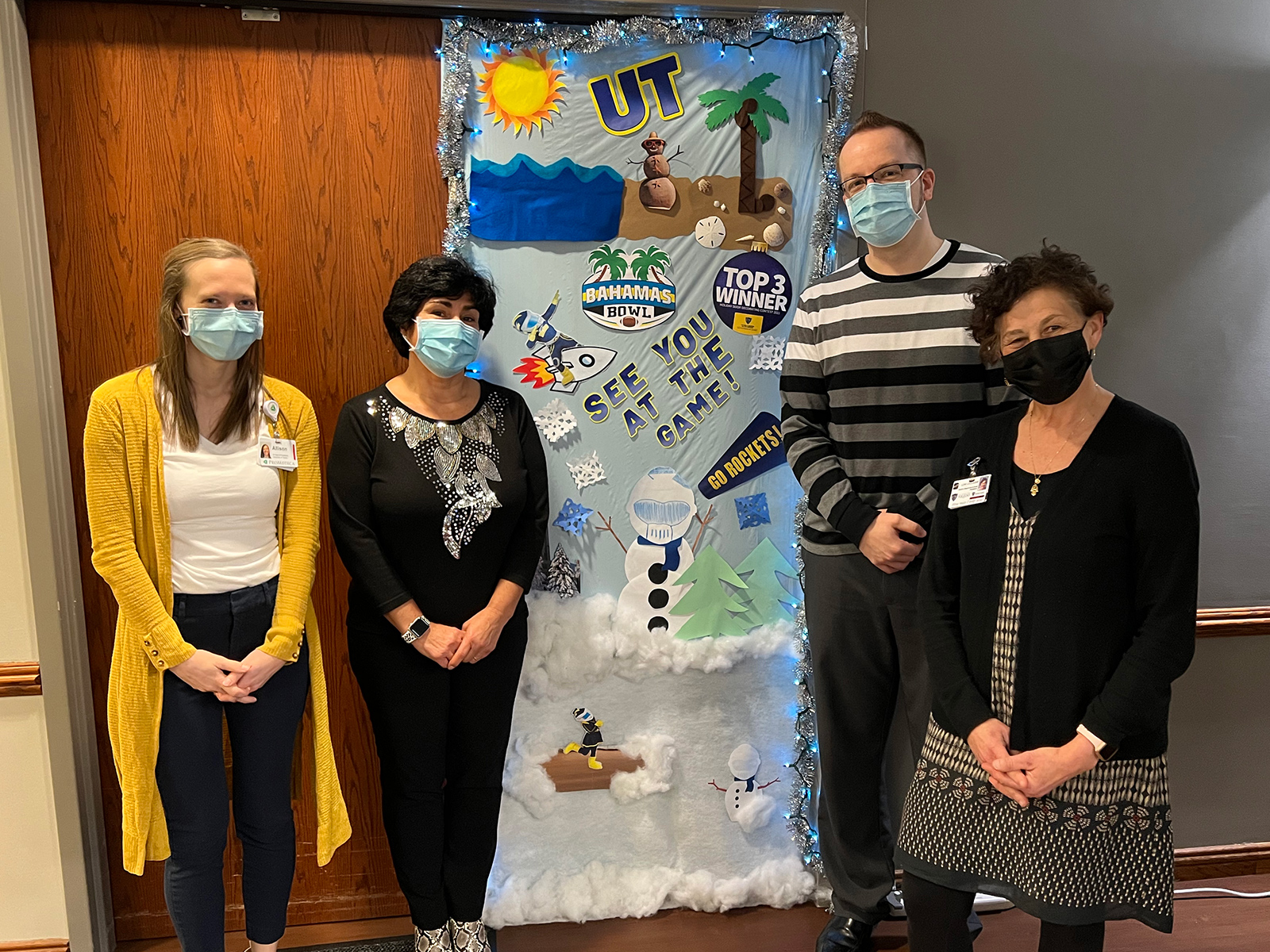 Staff members stand in front of their decorated door