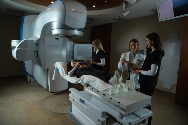 Faculty member instructing students in a radiation therapy room.