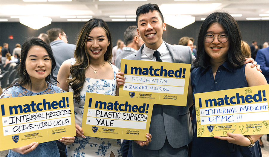 Photo of Match Day 2023 celebrations featuring four students holding signs.