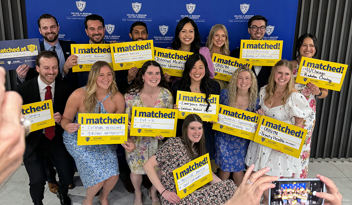 Photo of Match Day 2024 celebrations with a group of students pictured holding their signs in front of a blue and white UToledo backdrop.