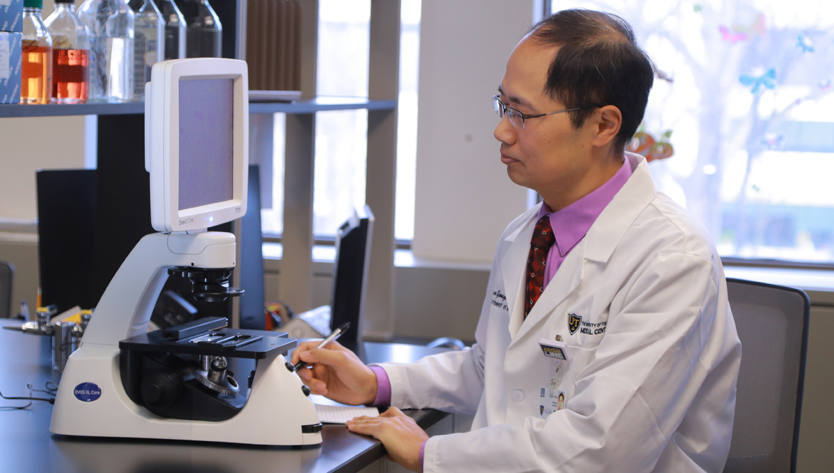 Photo of researcher in lab in front of microscope.