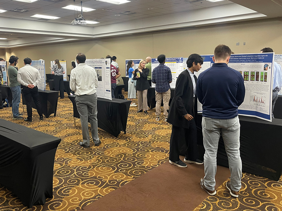 Attendees view and discuss research posters during the Medical Student Research Symposium, which showcased 50 second-year medical students' summer research projects.