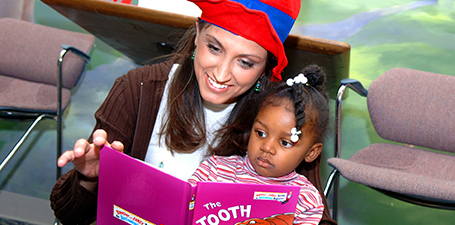 Photo of student reading a book to a child