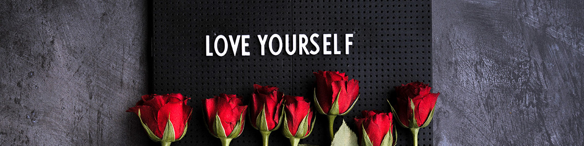 Stock photo of roses with a letterboard saying Love Yourself.