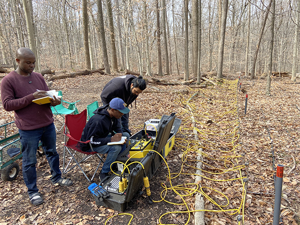 geophysics students working with electronic devices outside in the woods