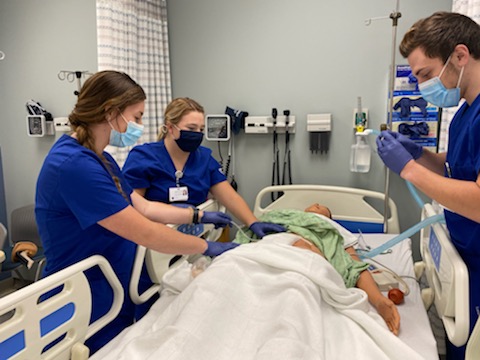 Nursing students practicing on a medical simulation mannequin