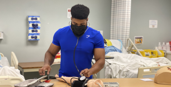 male student practicing taking blood pressure