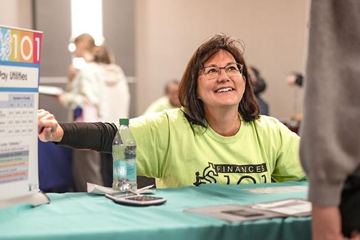 woman at financial wellness fair seated at booth with finances 101 chart