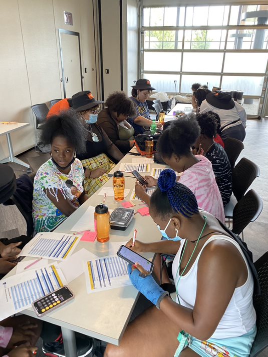 students at a table working on financial worksheets.