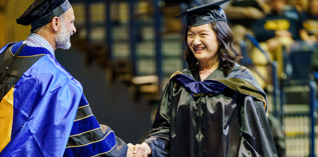 Graduate shaking hands with faculty at commencement