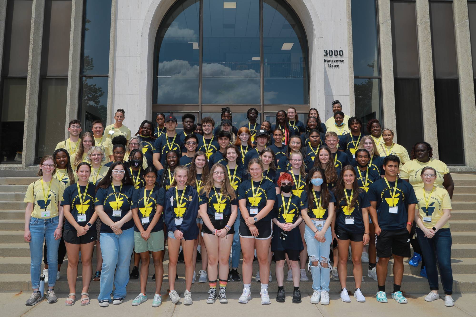 Group of students who participated in the pharmacy camp standing on the steps in front of a building