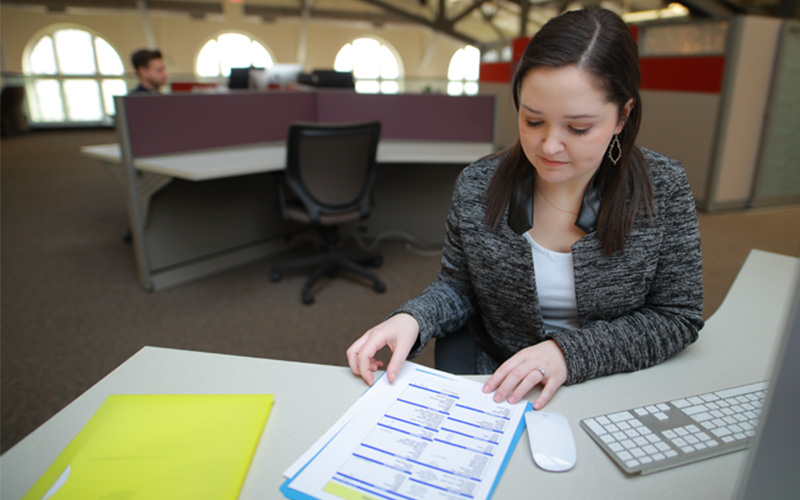 woman sitting at computer station observes a document displaying various tables of information
