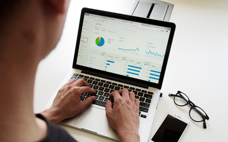 man observes data dashboard displaying pie charts, line graphs, and data on his laptop screen