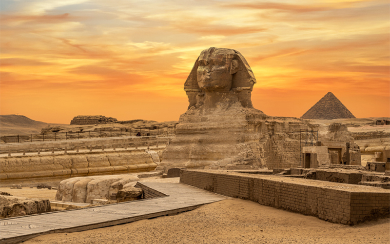 sunset landscape view of famous Ancient Egyptian structures featuring the pyramids