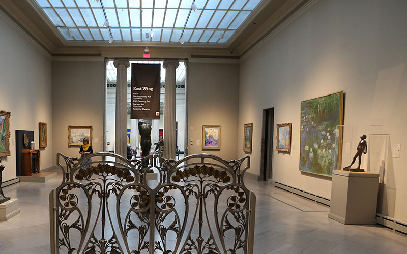 view inside the East Wing of the Toledo Art Museum featuring paintings displayed on the two walls to the left and right