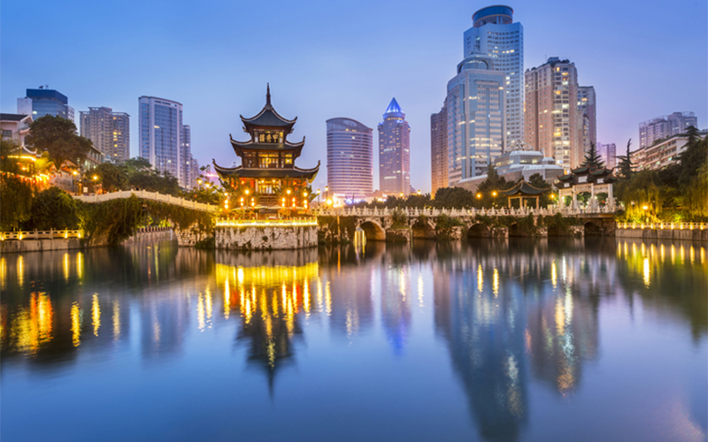Asian city skyline image at dusk with the building and bridge lights reflecting onto the water below