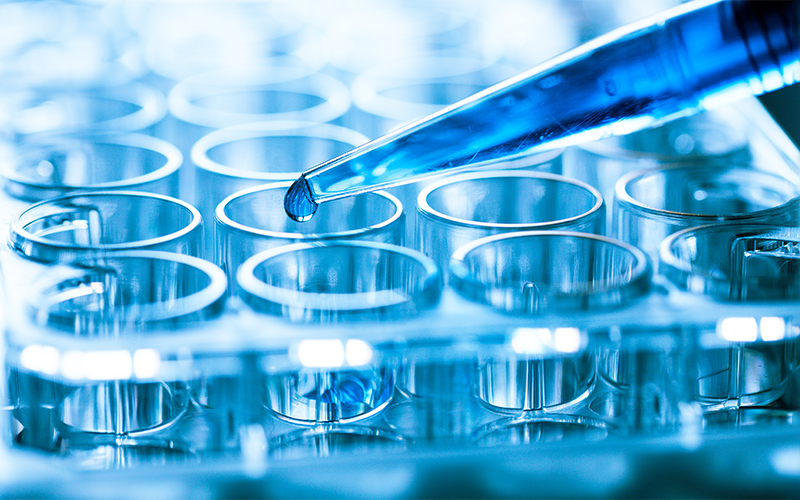 droplet drips liquid into small test tubes lined up in a row