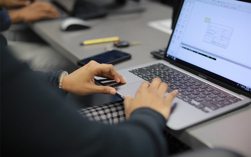 hands rest on laptop keyboard with data presented on the screen