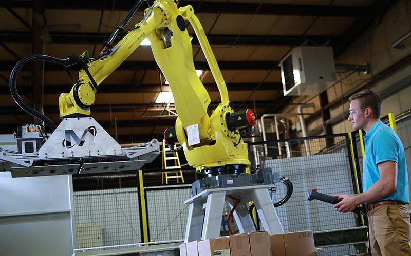 man wearing goggles holds a controller to power a yellow metal crane