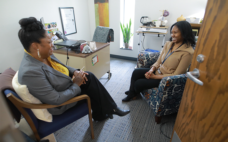 counseller in an office sitting in a chair talking to another person sitting in a chair