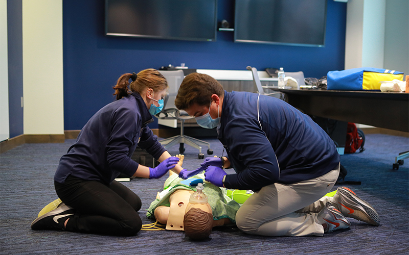 two students practice on a medical mannequin