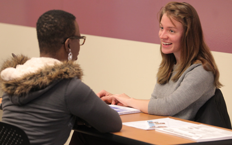 two students sit across from one another at a table
