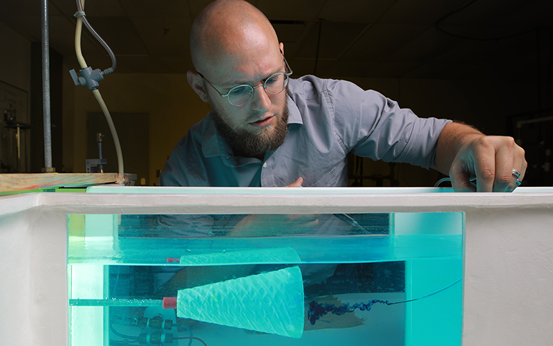 scientist squeezes dark blue drops into a test tank filled with water