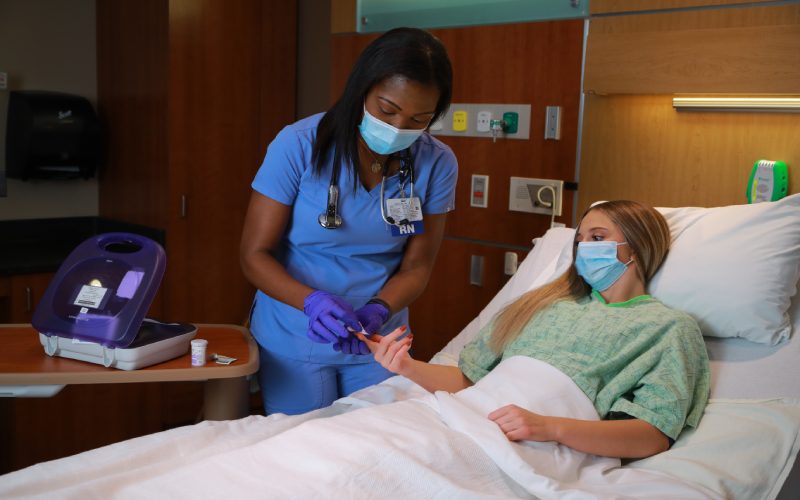 a nurse provides aid to a patient laying in a hospital bed