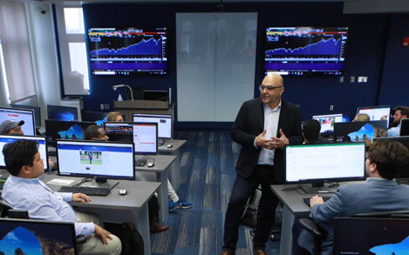students sit in computer lab and listen to the professor present during a lecture