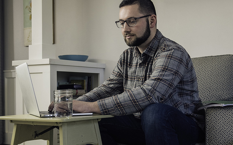 man typing on his laptop seated on a couch