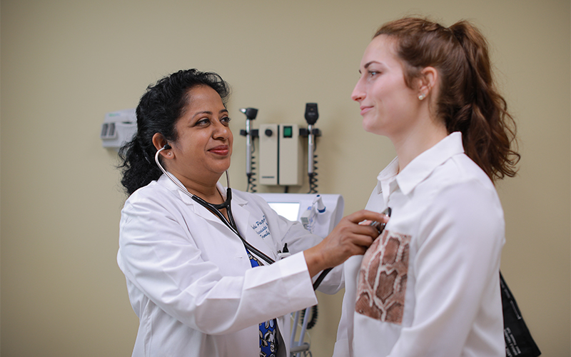 A docor using a stethoscope to check on a patients health