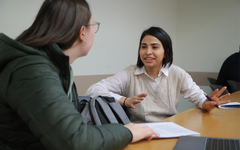 two students having a discussion at a table 
