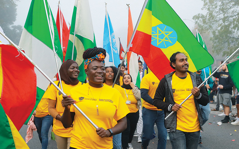 group of UToledo International Students carry various country flags in parade