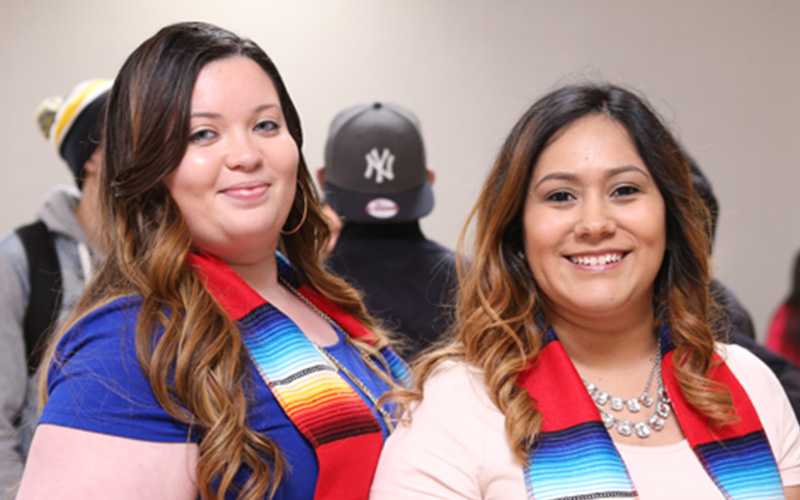 two students smile while wearing tri-colored Latin American sashes