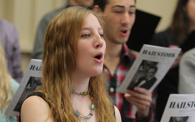female singer performs amongst a choir