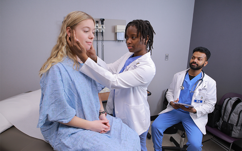 a physician assistant feels the area around the patient's jawline