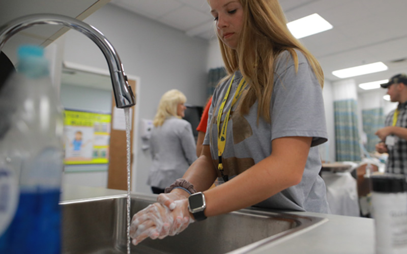 woman at a sink washes and sanitizes her hands