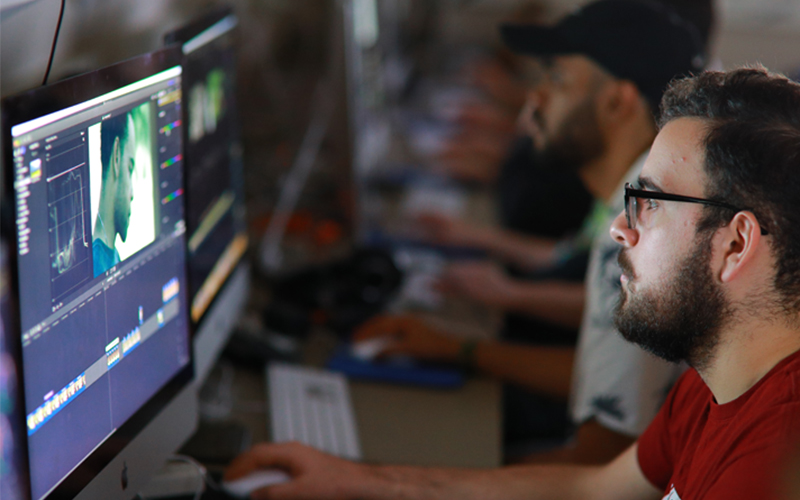 man observes computer screen displaying a video editing software
