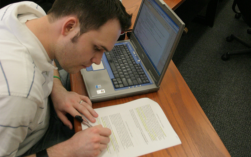 students takes annotates document packet and takes notes in front of open laptop