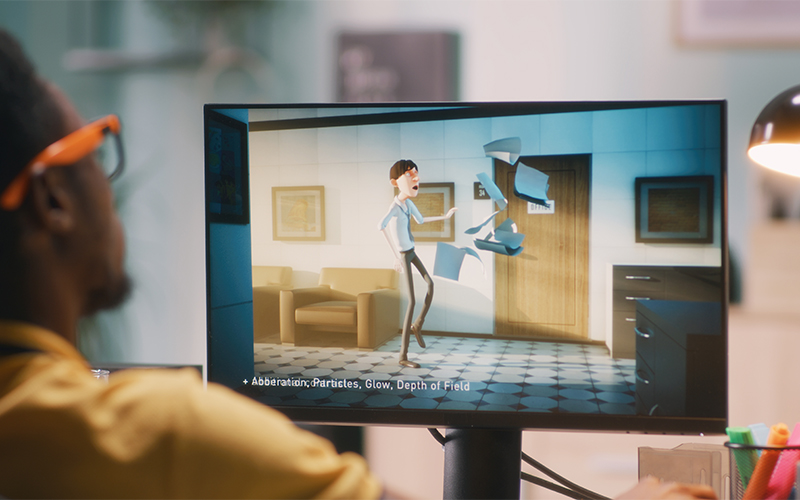man sits in front of compuer screen watching an animation project