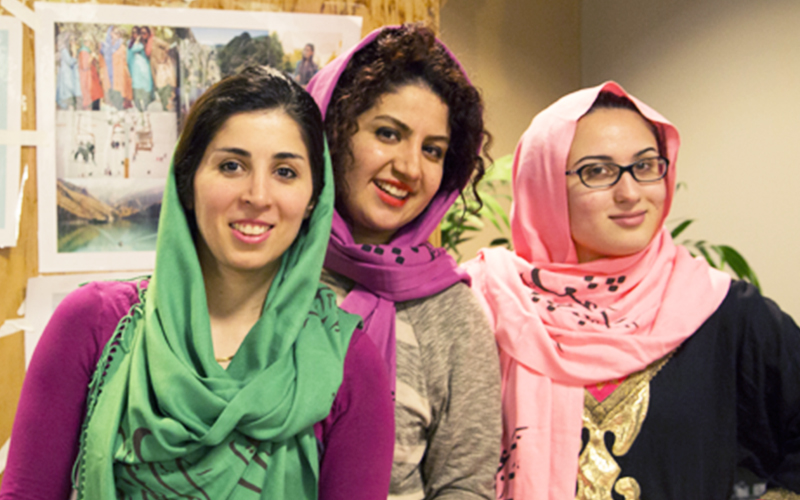 three students each wearing colorful headscarves smile