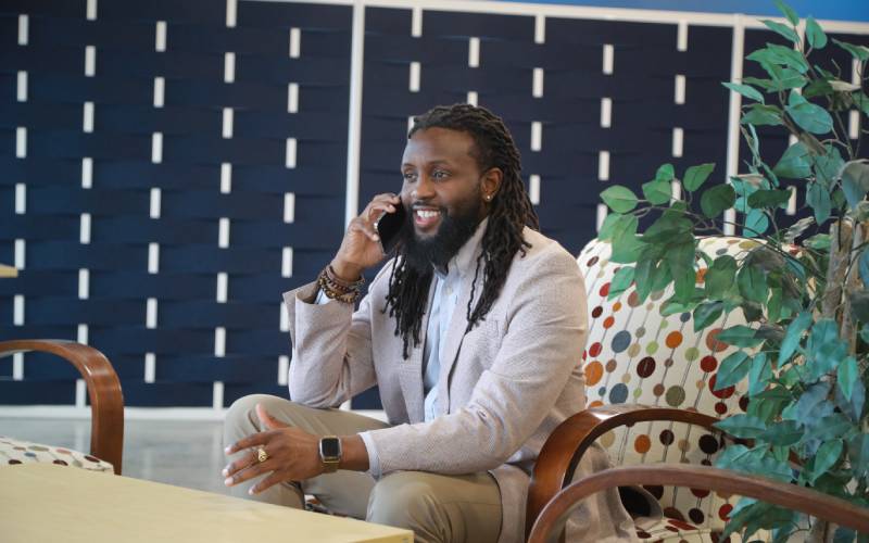 a man seated in a chair talks on the phone