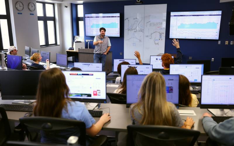 professor at the front of the classroom teaching a finance course