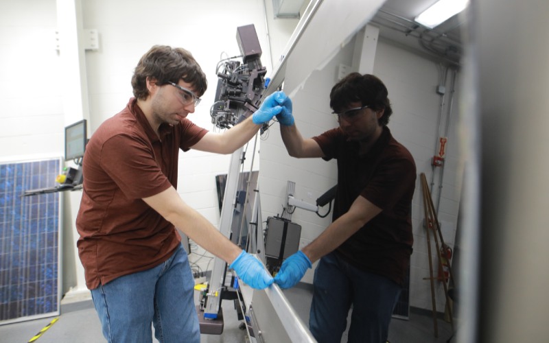 student with safety goggles adjusts lab machinery