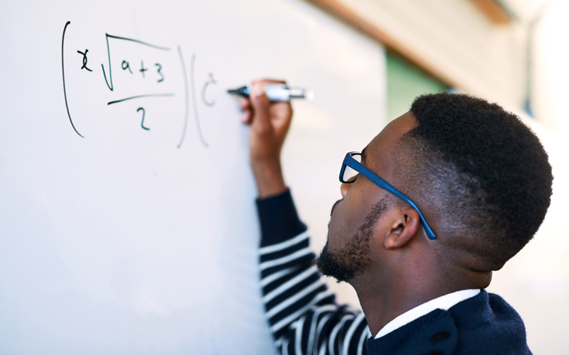 man writing math equation on white board