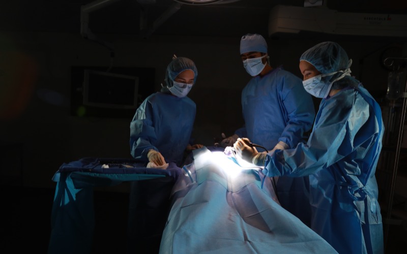 a group of surgeons dressed in blue scrubs performing surgery