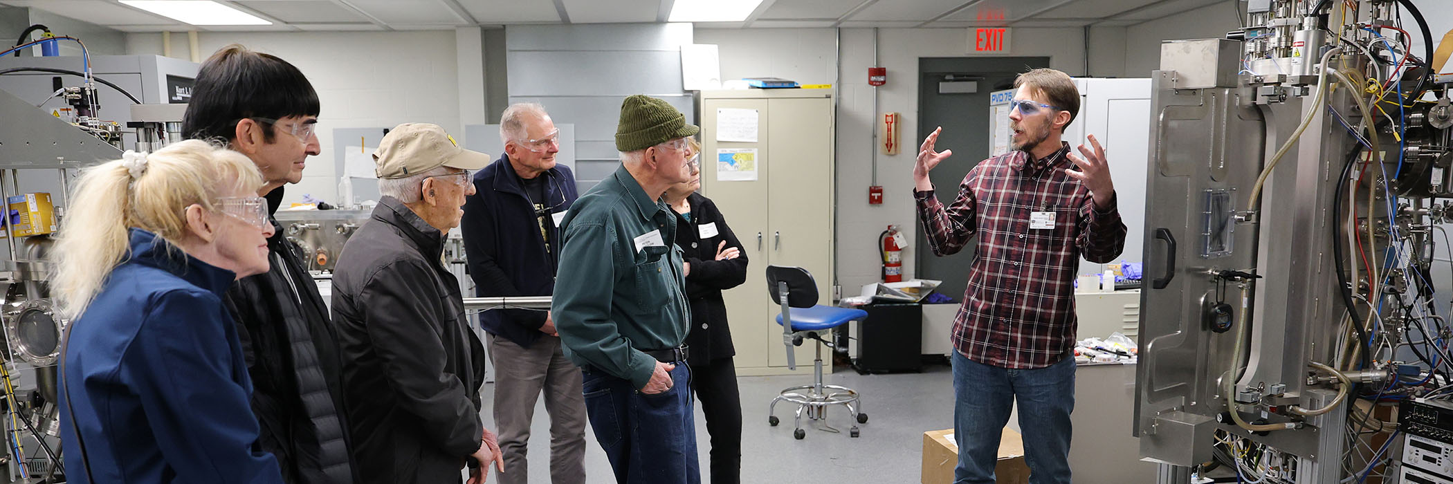 A man explaining something to a group of individuals in a research space with equipment