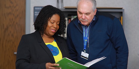 African American Woman and White Man looking at a green folder