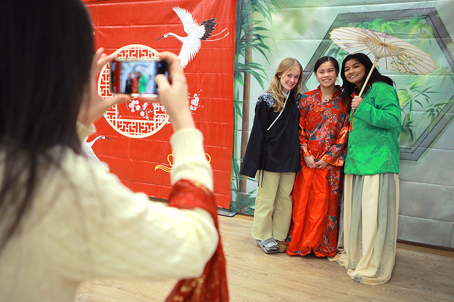 three girls dressed up in cultural outfits posing for a photo