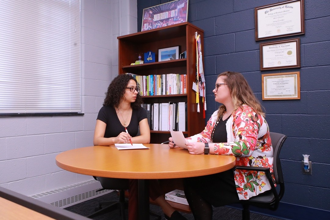 two students talking at table